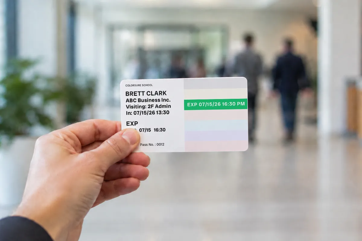 A color-banded visitor badge held up in a lobby